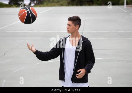 Männliche Teenager basketball Player auf basketballplatz Werfen und Fangen ball Stockfoto