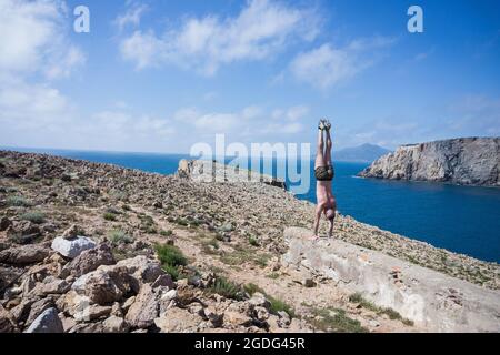 Mann macht Handstand auf einem Hügel, Iglesias, Sardinien, Italien Stockfoto