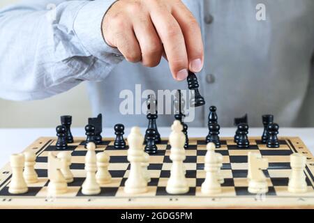 Mann spielt Schachspiel, Hand bewegt Schach Stück auf Schachbrett. Erfolgskonzept der Finanzgeschäftsstrategie Stockfoto