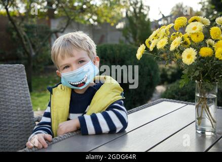 Gezeichnet lustige Lächeln auf einer blauen Anti-Virus-Maske. Eine lustige DIY Gesichtsmaske für die Sicherheit in einer Pandemie oder Quarantäne. Lächeln Sie und bleiben Sie sicher. Keine Sorge Verwenden Sie eine Maske Stockfoto