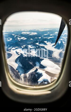 Luftbild von Bergen und Gletschern aus dem Flugzeugfenster. Stockfoto