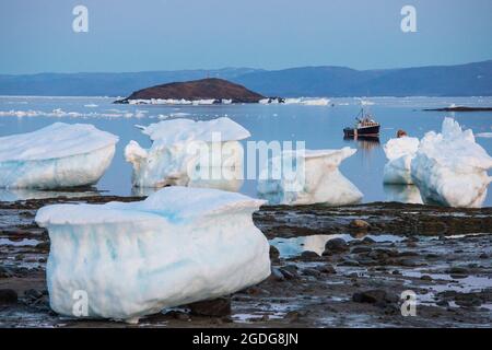 Boot im Hafen von Iqaluit neben dem Meereis verankert. Stockfoto