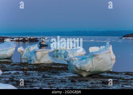 Kleines Boot, das zwischen großen Eisbrocken in Iqaluit, Kanada, festgemacht ist. Stockfoto