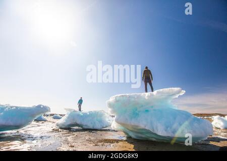 Zwei Männer, die auf Meereisbrocken stehen, Iqaluit, Kanada. Stockfoto