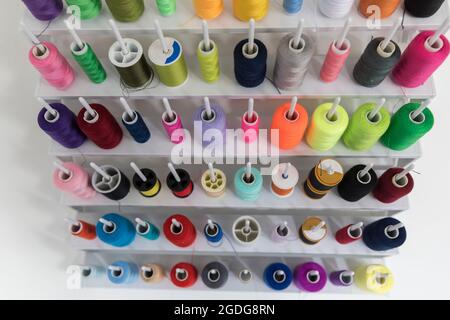 Eine große Auswahl an bunten Baumwollfäden, die auf Spulen angeordnet sind. Stockfoto