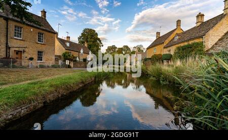 Cotswolds lower Slaughter Cottages spiegeln sich bei Sonnenuntergang am wunderschönen Himmel wider Stockfoto