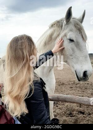 Junge Frau streicheln Pferd und Stall stehend Stockfoto