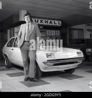 1975, historisch, ein Autoverkäufer in einem Showroom, der neben einem neuen Auto steht, einem Vauxhall Chevette 3-türigen Heckklappe, Croydon, England, Großbritannien. Der Chevette, der im Rahmen einer Regierungsinitiative zur Schaffung von Arbeitsplätzen in der Region im Ellesmere Port in Cheshire hergestellt wurde, wurde von 1975 bis 1984 produziert und war in den drei Jahren bis 1978 Großbritanniens meistverkauftes Fließheck. Die 1970er Jahre waren eine Zeit, in der kompakte Heckwagen ein beliebtes Fahrzeug waren. Stockfoto