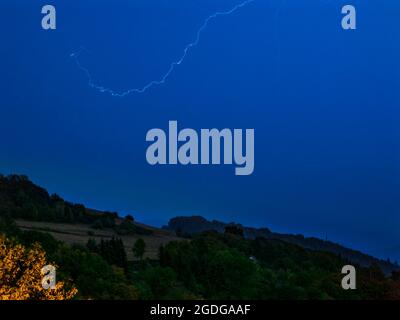 Blitz in den Himmel über der hügeligen Landschaft - lange Belichtung in der Nacht Stockfoto