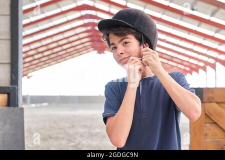 Teenager, der einen Reithelm auf den Kopf setzt. Stockfoto