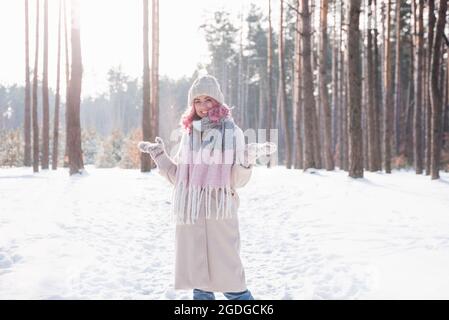 Winterfrau, die am kalten Wintertag im Schnee fröhlich aufschaut und lächelt Stockfoto