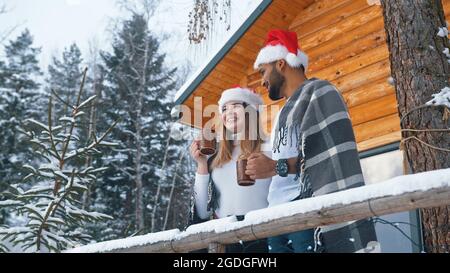 Ein glückliches Paar mit Tassen in den Händen genießt die Winteridylle. Hochwertige Fotos Stockfoto