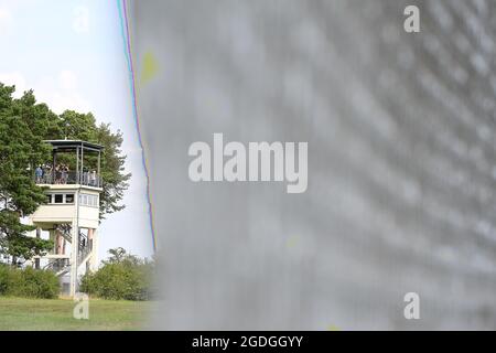 Geisa, Deutschland. August 2021. Blick auf einen ehemaligen Aussichtsturm hinter einem Grenzzaun an der Point Alpha Gedenkstätte. Zum Gedenken an den Bau der Berliner Mauer vor 60 Jahren und die innerdeutsche Teilung wurde eine Gedenkveranstaltung abgehalten. Quelle: Swen Pförtner/dpa-Zentralbild/dpa/Alamy Live News Stockfoto