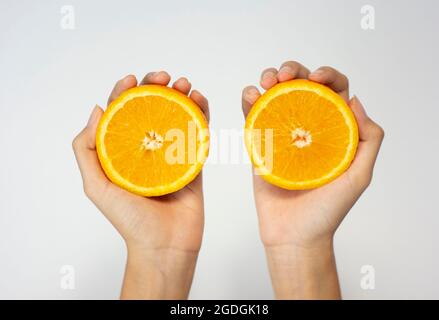 Nahaufnahme der Hände, die orangefarbene Scheiben von Sunkist halten, isolierter weißer Hintergrund Stockfoto