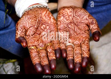Das wunderschöne Kunstwerk von Henna Mehndi auf den schönen Händen des indischen Bräutigams wird Henna-Farbstoff während des indischen Hochzeitsfestes auf die Hand des Mannes aufgetragen Stockfoto