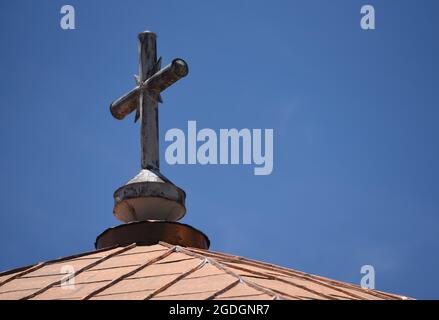 Zinnkreuz auf dem mit Kupferblättern bedeckten Dach der historischen Metropole Aghia Kyriaki, einem Wahrzeichen im ländlichen Dorf Dimitsana, Arcadia Griechenland. Stockfoto