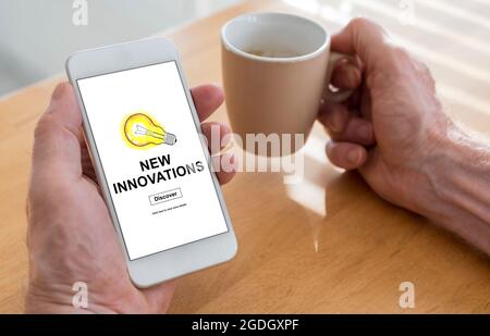 Männliche Hände halten ein Smartphone mit neuem Innovationskonzept und einer Tasse Kaffee Stockfoto