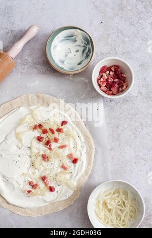 Zubereitung eines traditionellen Flammkuchen mit Creme fraiche, Fromage Blanc, Lardonen und Zwiebeln. Stockfoto