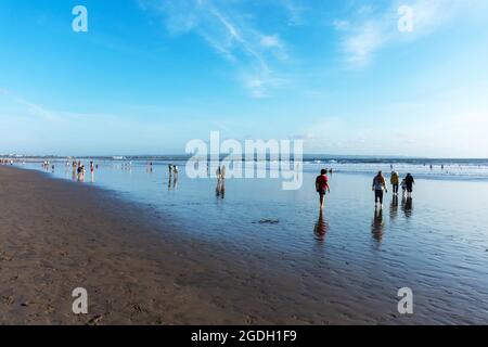 Kuta, Indonesien - 14. September 2018: Touristen und Einheimische bummeln und genießen den Sonnenuntergang am Seminyak-Strand auf Bali. Es ist eine der Touristenattraktionen in Stockfoto