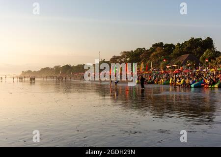 Kuta, Indonesien - 14. September 2018: Touristen und Einheimische bummeln und genießen den Sonnenuntergang am Seminyak-Strand auf Bali. Es ist eine der Touristenattraktionen in Stockfoto