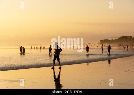 Kuta, Indonesien - 14. September 2018: Touristen und Einheimische bummeln und genießen den Sonnenuntergang am Seminyak-Strand auf Bali. Es ist eine der Touristenattraktionen in Stockfoto