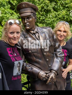 Bad Nauheim, Deutschland. August 2021. Die Initiatoren Angela Storm (l.) und Meike Berger enthüllen eine lebensgroße Bronzestatue der Rock'n'Roll-Legende Elvis Presley an der Stelle, an der er sich während seiner eineinhalb Jahre in der Armee an ein Brückengeländer im hessischen Kurort lehnte. Das '19. European Elvis Festival 2021' findet in Bad Nauheim statt. Quelle: Helmut Fricke/dpa/Alamy Live News Stockfoto