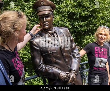 Bad Nauheim, Deutschland. August 2021. Die Initiatoren Angela Storm (l.) und Meike Berger enthüllen eine lebensgroße Bronzestatue der Rock'n'Roll-Legende Elvis Presley an der Stelle, an der er sich während seiner eineinhalb Jahre in der Armee an ein Brückengeländer im hessischen Kurort lehnte. Das '19. European Elvis Festival 2021' findet in Bad Nauheim statt. Quelle: Helmut Fricke/dpa/Alamy Live News Stockfoto