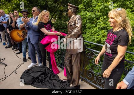 Bad Nauheim, Deutschland. August 2021. Die Initiatoren Angela Storm (2. Von rechts) und Meike Berger (rechts) enthüllen eine lebensgroße Bronzestatue der Rock'n'Roll-Legende Elvis Presley an der Stelle, an der er sich während seines eineinhalbjährigen Militärdienstes an ein Brückengeländer im hessischen Kurort lehnte. Das '19. European Elvis Festival 2021' findet in Bad Nauheim statt. Quelle: Helmut Fricke/dpa/Alamy Live News Stockfoto