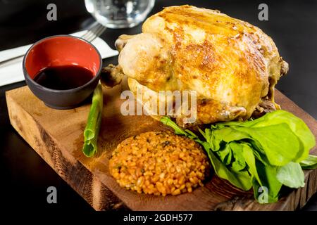 Gebratenes Huhn auf Holzkohle mit Bulgur-Pilaf auf einem weißen Porzellanteller gekocht. Stockfoto