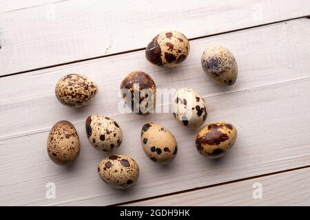 Mehrere Wachteleier, Nahaufnahme, auf einem weißen Holztisch, Draufsicht. Stockfoto