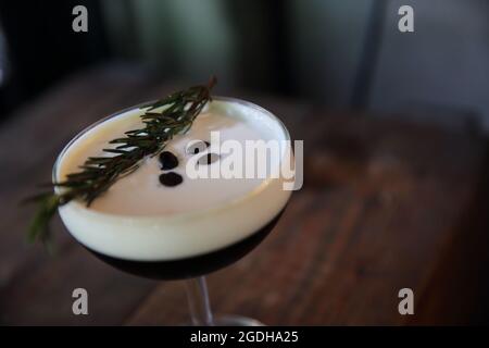 Kaffeecocktail mit Kaffeebohne und Rosmarin auf der Oberseite mit Holzhintergrund Stockfoto