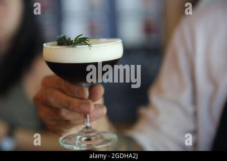 Kaffeecocktail mit Kaffeebohne und Rosmarin auf der Oberseite mit Holzhintergrund Stockfoto