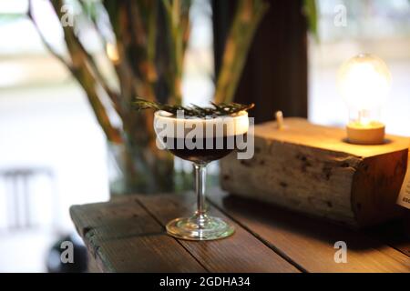 Kaffeecocktail mit Kaffeebohne und Rosmarin auf der Oberseite mit Holzhintergrund Stockfoto