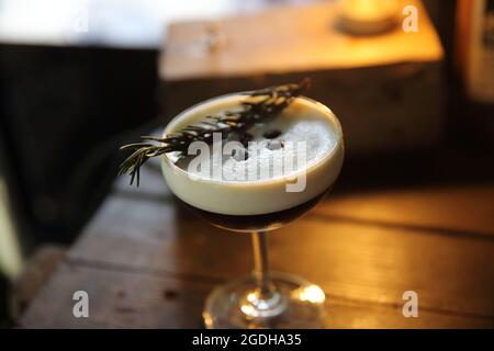 Kaffeecocktail mit Kaffeebohne und Rosmarin auf der Oberseite mit Holzhintergrund Stockfoto