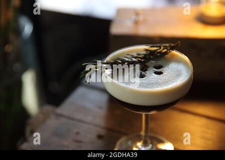 Kaffeecocktail mit Kaffeebohne und Rosmarin auf der Oberseite mit Holzhintergrund Stockfoto