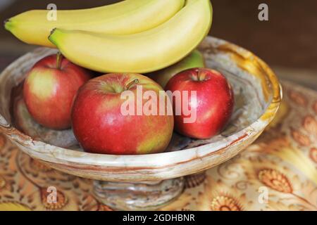 Äpfel und Bananen in einer Marmorplatte Stockfoto