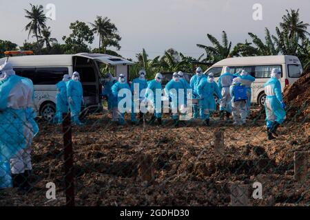 Kuala Lumpur, Malaysia. August 2021. Arbeiter in Schutzanzügen tragen den Leichnam eines COVID-19-Opfers auf einem Friedhof in Selangor, Malaysia, 13. August 2021. Malaysia verzeichnete 21,468 neue COVID-19-Infektionen, teilte das Gesundheitsministerium am Freitag mit und brachte damit die landesweite Gesamtzahl auf 1,363,683. Quelle: Chong Voon Chung/Xinhua/Alamy Live News Stockfoto