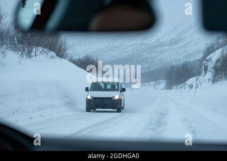 Weißer Van, der am verschneiten Tag auf der Autobahn fährt und Schnee von Schneesturm bedeckt ist Stockfoto