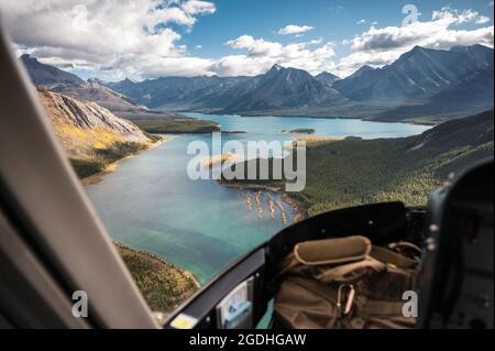 Im Inneren des Hubschraubers, der auf felsigen Bergen mit türkisfarbenem See und blauem Himmel im Banff National Park, Kanada, fliegt Stockfoto