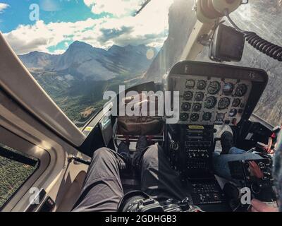 Im Cockpit fliegt ein Hubschrauber über die Rocky Mountains im Nationalpark. POV-Aufnahme Stockfoto