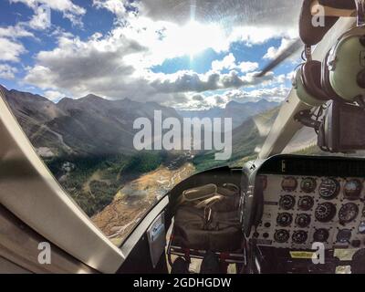 Im Cockpit fliegt ein Hubschrauber über die Rocky Mountains im Nationalpark. POV-Aufnahme Stockfoto