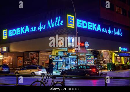 Berlin; Deutschland - 23. Juni; 2021: Nachtaufnahme eines offenen Kiosk an der Ecke eines beleuchteten Supermarkts in der Berliner Innenstadt. Stockfoto