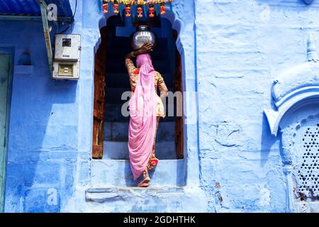 Jodhpur, Indien - 28. Februar 2018: Indische Frau trug Wasser im Topf auf ihrem Kopf in der blauen Stadt Jodhpur. Stockfoto