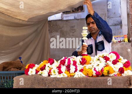 Jodhpur, Indien - 28. Februar 2018: Indiens Mann macht eine bunte Blumengirlande. Stockfoto