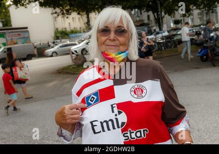 Hamburg, Deutschland. August 2021. Fußball: 2. Bundesliga, FC St. Pauli - Hamburger SV, Matchday 3, Millerntor-Stadion. Jutta Kröger (77) hat sich aus dem St. Pauli Trikot und dem HSV Trikot ein Overall-Trikot gemacht und steht damit in der Nähe des Stadions. Quelle: Markus Scholz/dpa - WICHTIGER HINWEIS: Gemäß den Bestimmungen der DFL Deutsche Fußball Liga und/oder des DFB Deutscher Fußball-Bund ist es untersagt, im Stadion und/oder vom Spiel aufgenommene Fotos in Form von Sequenzbildern und/oder videoähnlichen Fotoserien zu verwenden oder zu verwenden./dpa/Alamy Live News Stockfoto