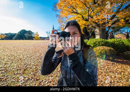 Frau, die mit einer digitalen spiegellosen Kamera in den Gärten von Tokio ein Foto gemacht hat Stockfoto
