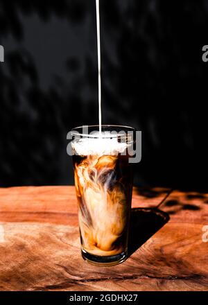 Gerade aus Sicht der Creme, die in kalten Brühkaffee gegossen wird Stockfoto