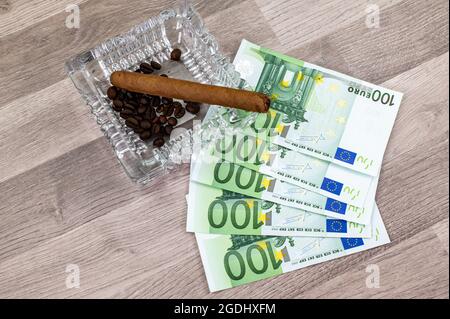 100 Euro Scheine und Aschenbecher mit Zigarre auf Holztisch Stockfoto