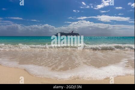 Half Moon Cay, Bahamas - 19. Februar 2020: Carnival Freedom ankern auf der Insel Half Moon Cay. Wunderschönes türkisfarbenes Wasser, das im Vordergrund spritzt. Stockfoto