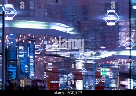 Deckenleuchten werden in Glas reflektiert und erzeugen blaues Licht mit vielen Strukturen. Stockfoto